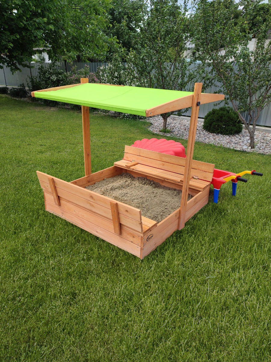 "Houten zandbak met deksel en bank, met groen dakje, in de tuin."