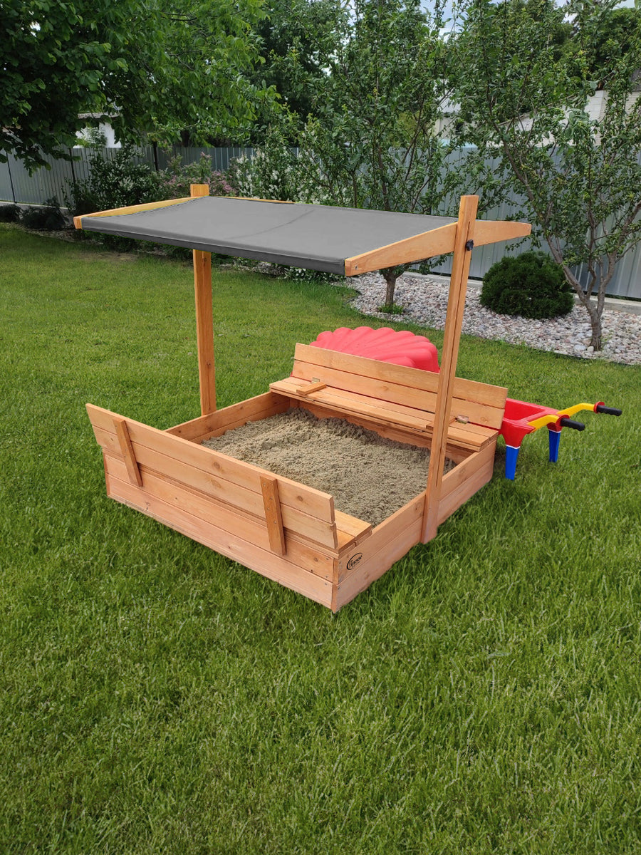 Houten zandbak met bank, grijs dakje, open zandbak met bankjes in een groene tuin, ideaal voor kinderen.