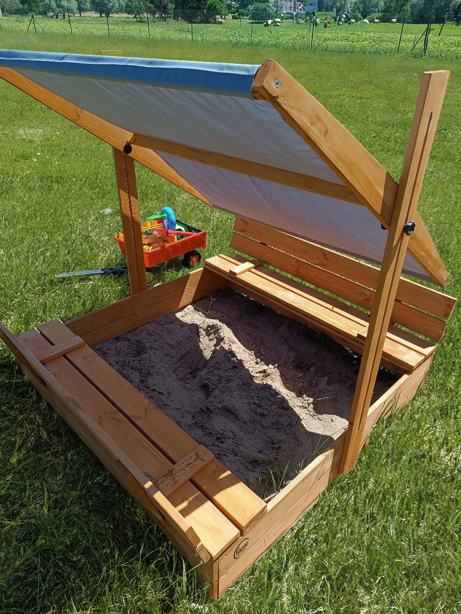 Houten zandbak met bank, blauw dakje, open zandbak met bankjes in een groene tuin, ideaal voor kinderen.