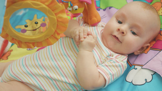 Speelkleed voor baby's met boog, in grijze kleur met konijnmotief, inclusief speeltjes en kussen.
