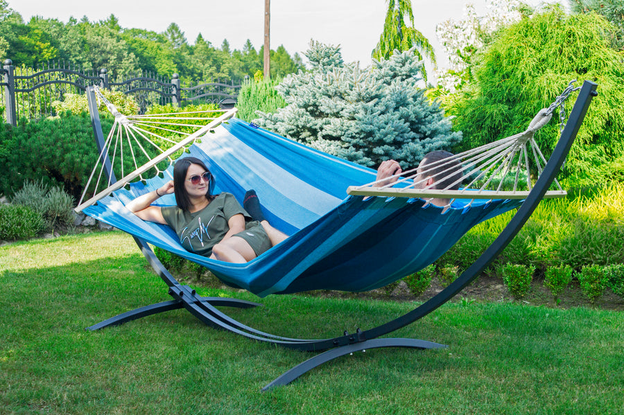 "Heerlijk ontspannen in de tuin met een blauw gestreepte 2-persoons hangmat met standaard, het Acadia-type."